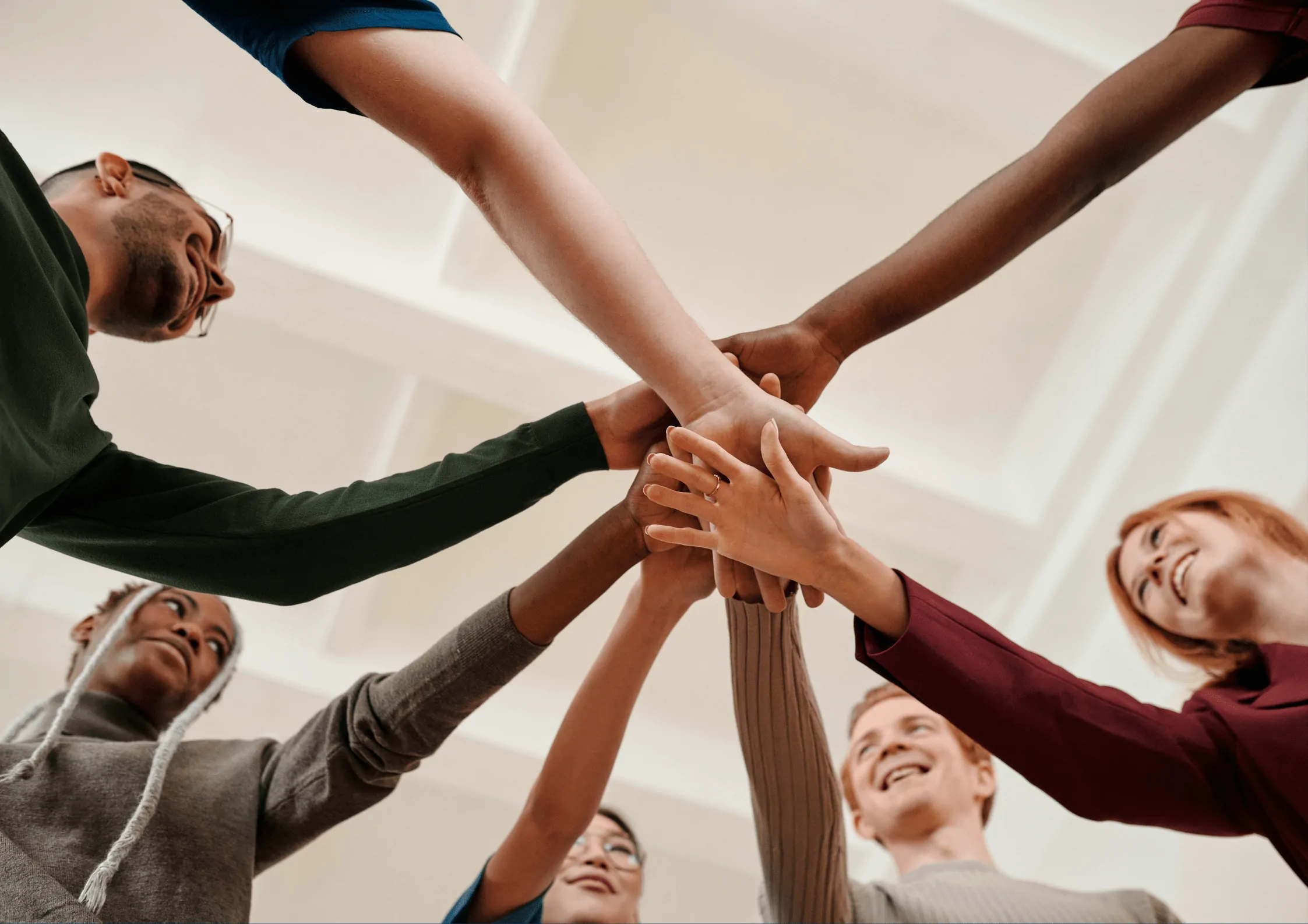 Imagem principal de um post de blog retratando pessoas diversas com as mãos unidas, representando trabalho em equipe.