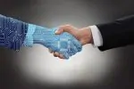 Close-up Of Two Businessman Shaking Hands In Front Of Mallet